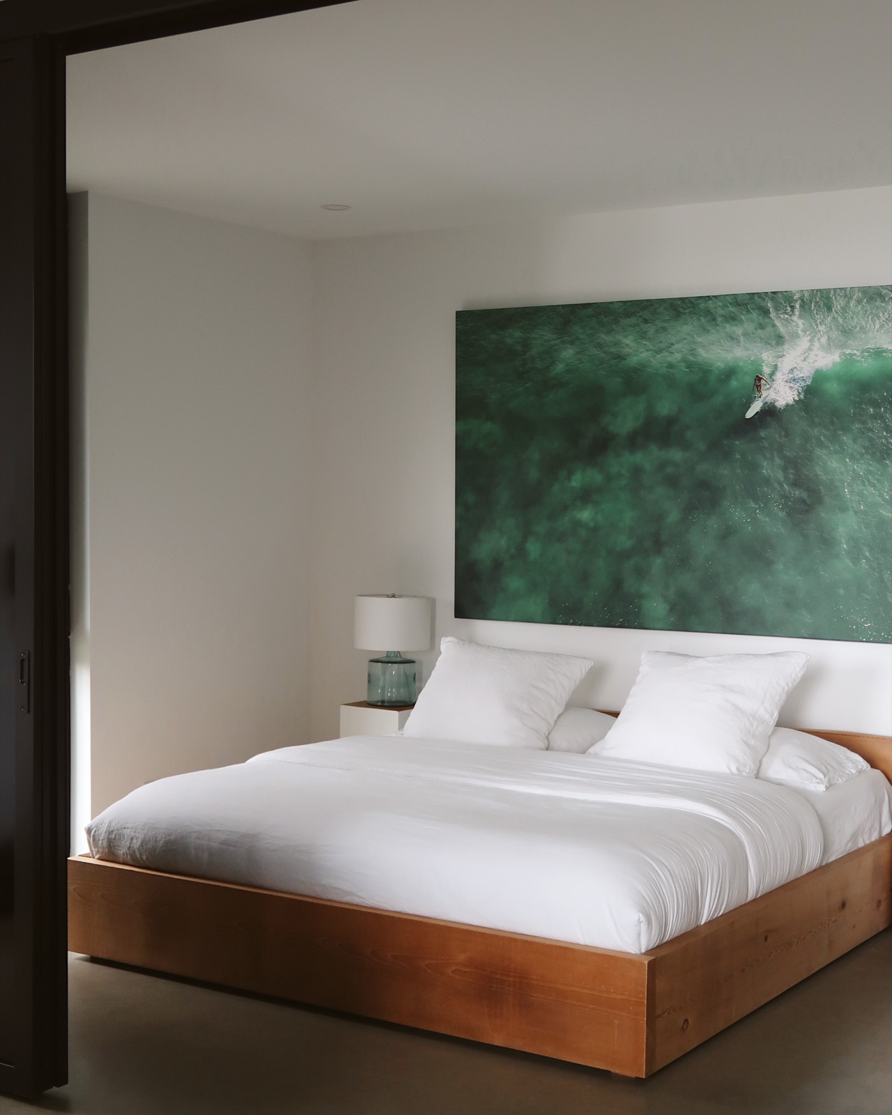 Bedroom with crisp white linens beneath a green ocean artwork