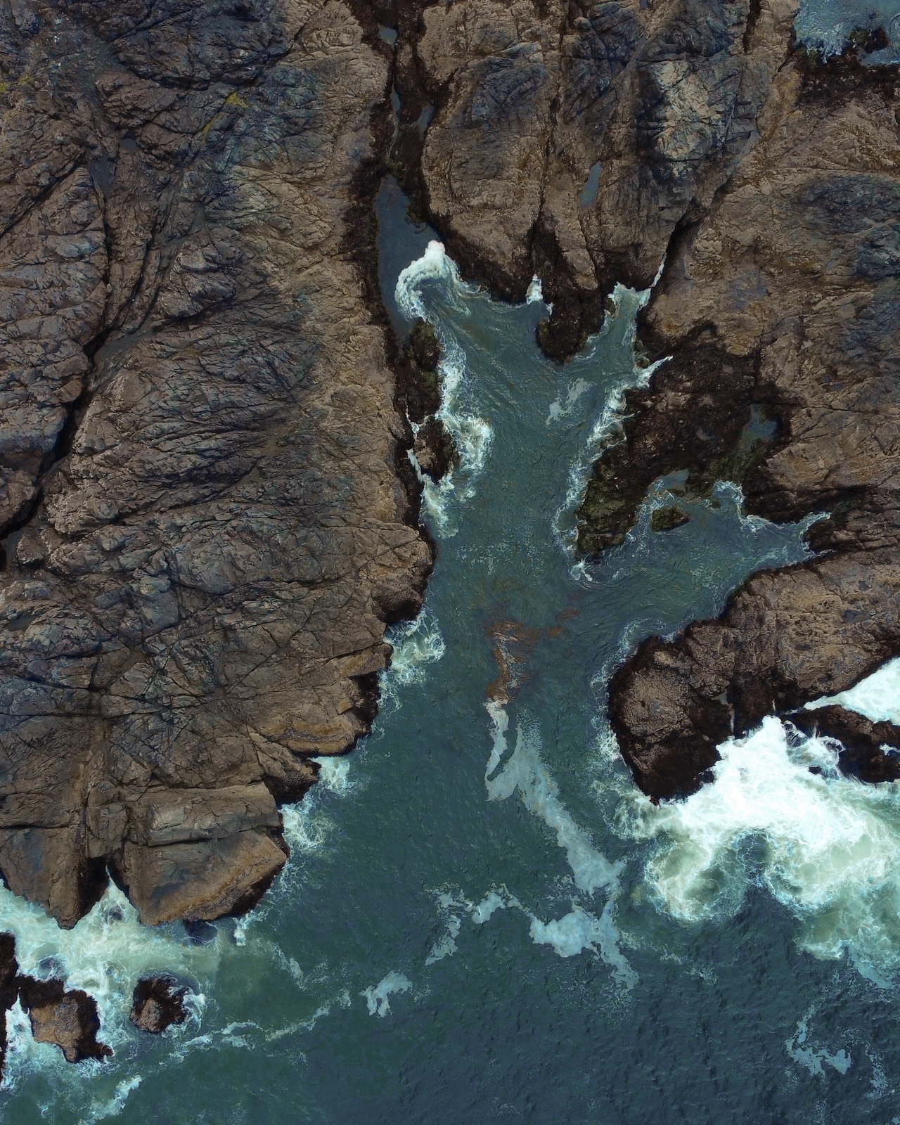 Aerial of the rugged coastline and turquoise surf below the property