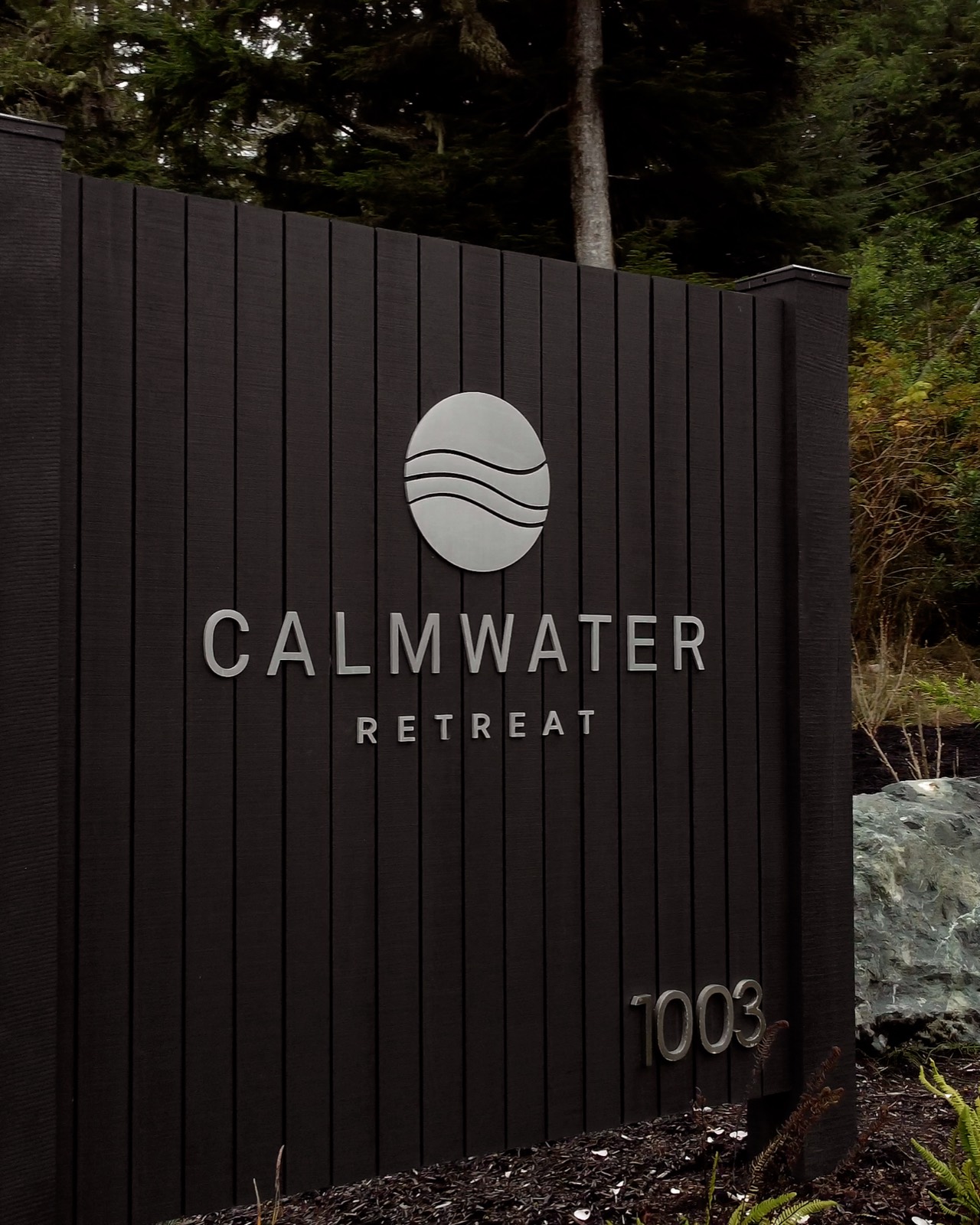 Calmwater Retreat signage on a dark cedar wall