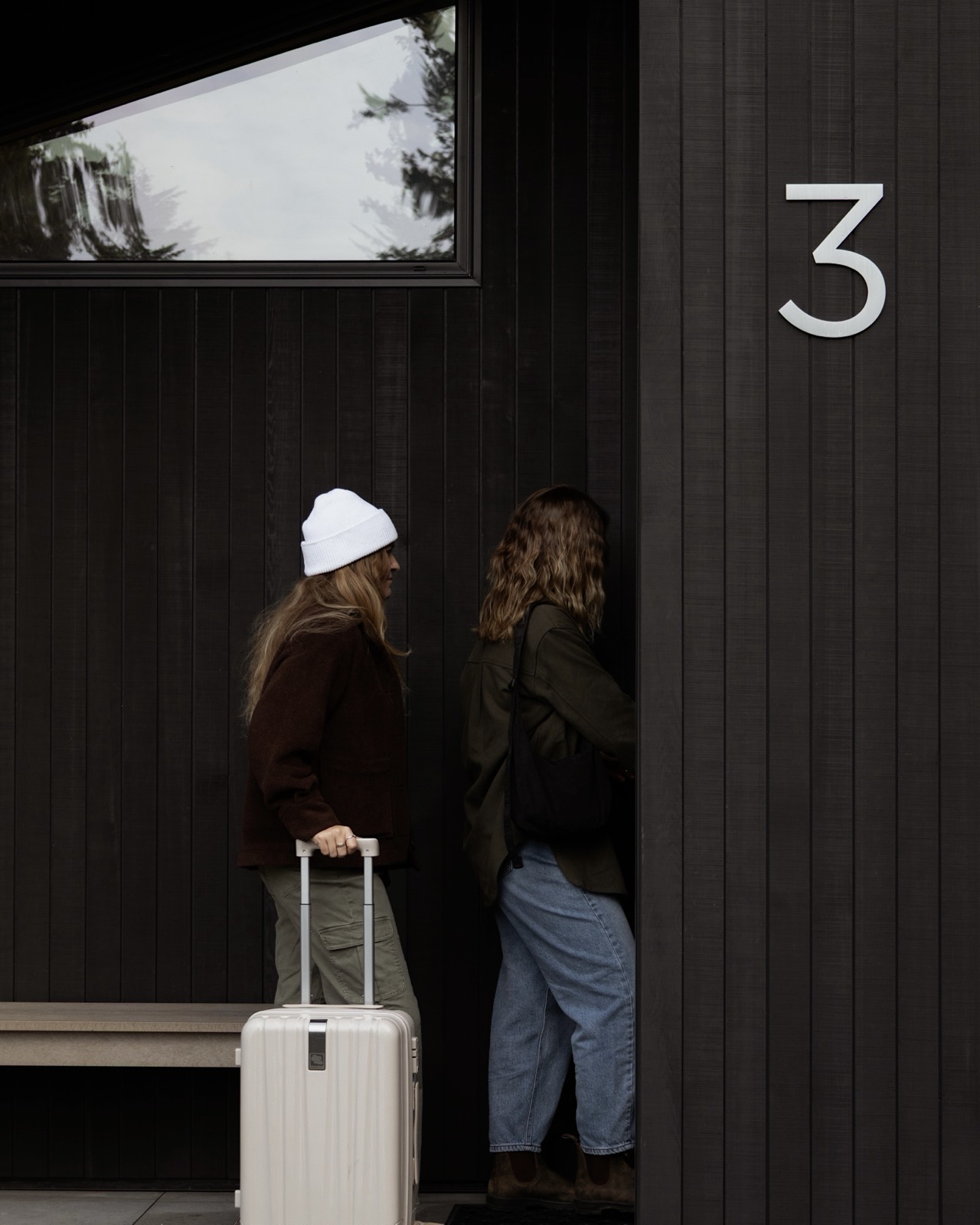 Two guests arriving at a cabin with a surfboard