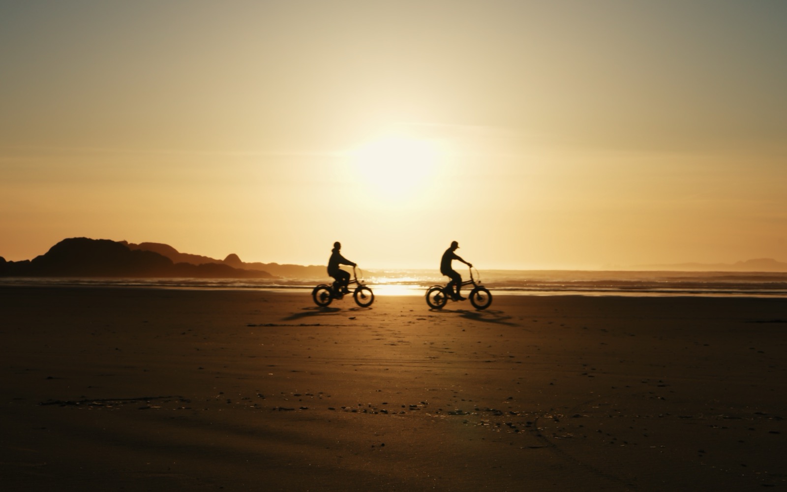 Jordan and Kaitlyn biking along the beach at sunset