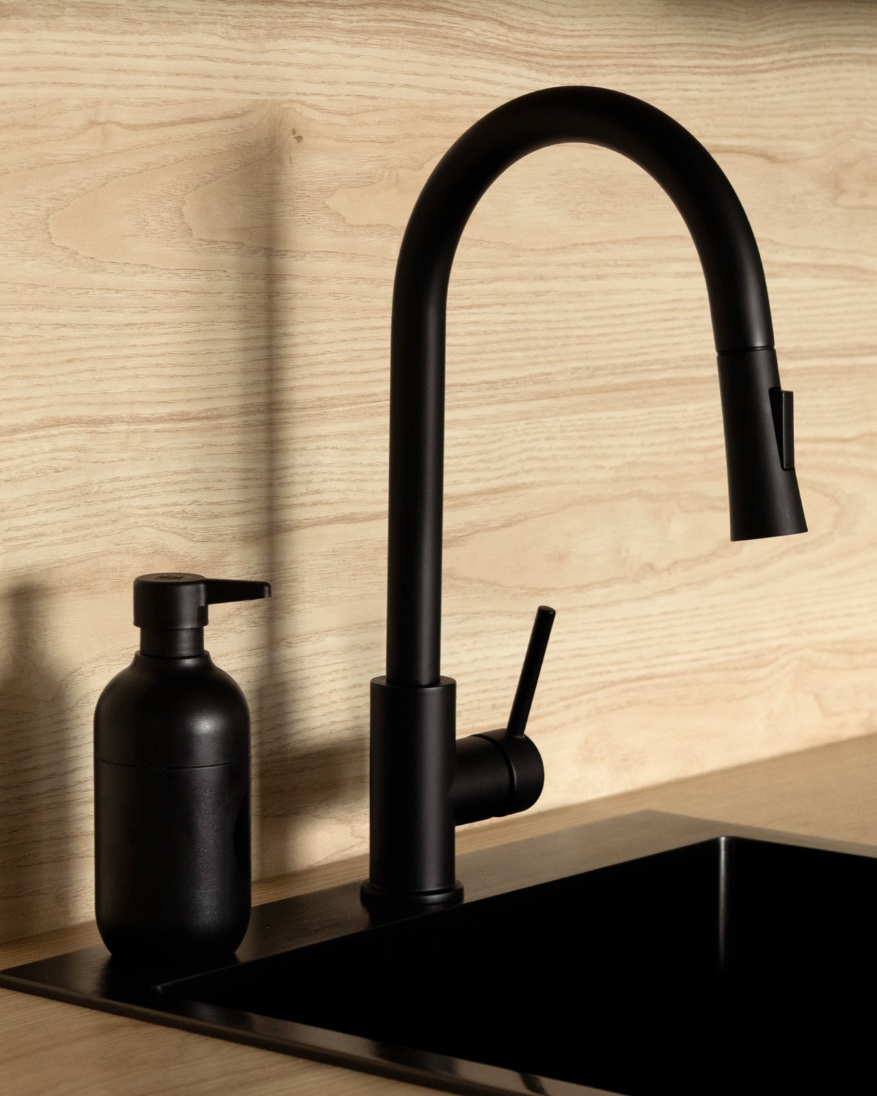 Matte black kitchen faucet on a warm wood counter