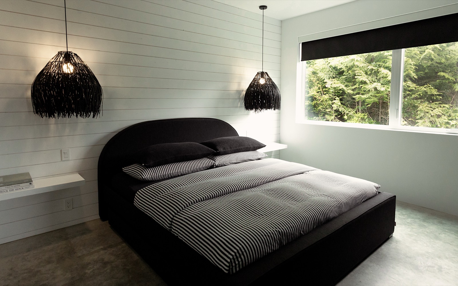 A moody bedroom with a pendant light and dark linens