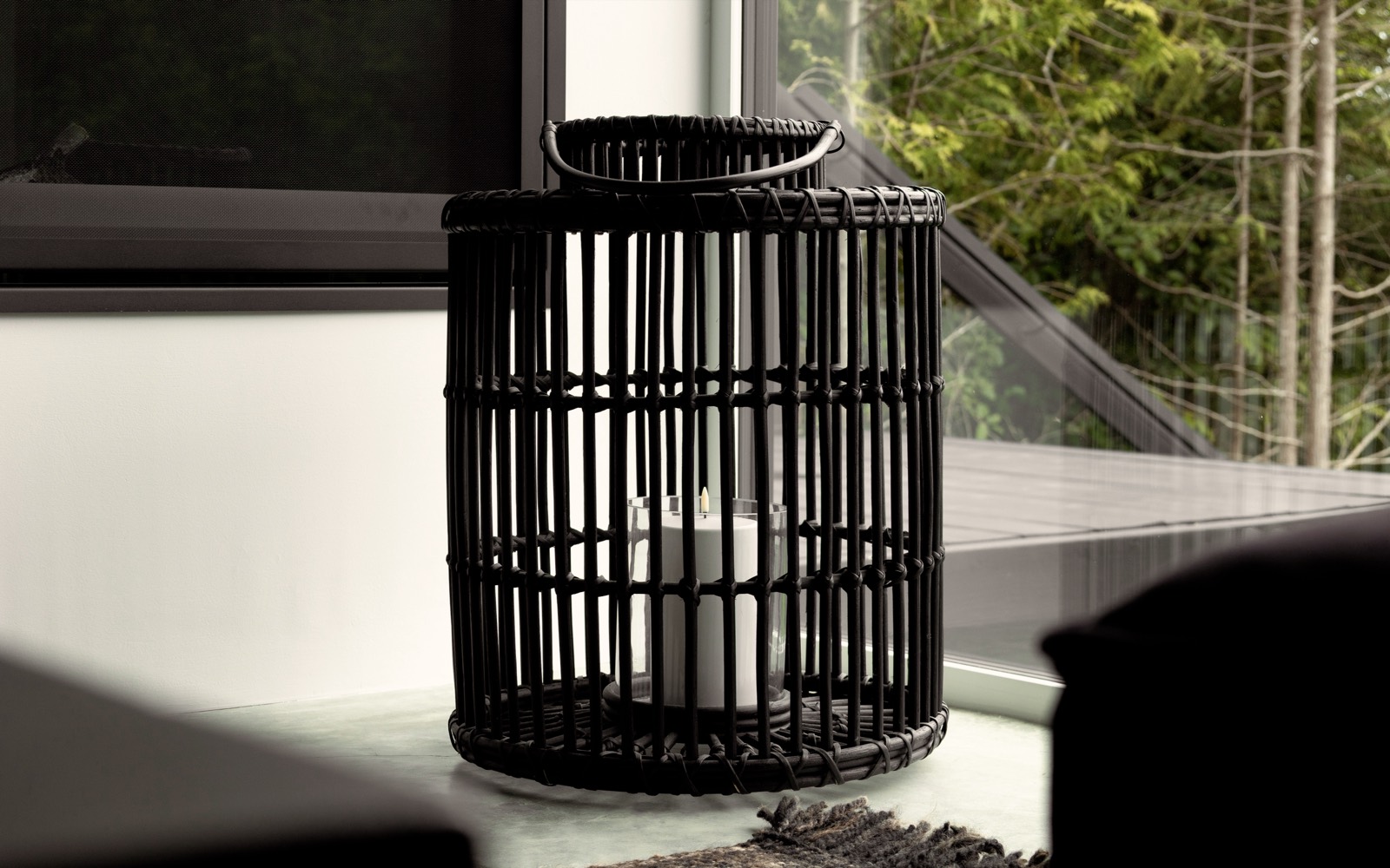 A black lantern on the deck, forest soft behind it